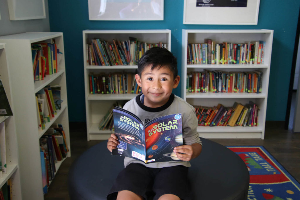 young boy reading in library
