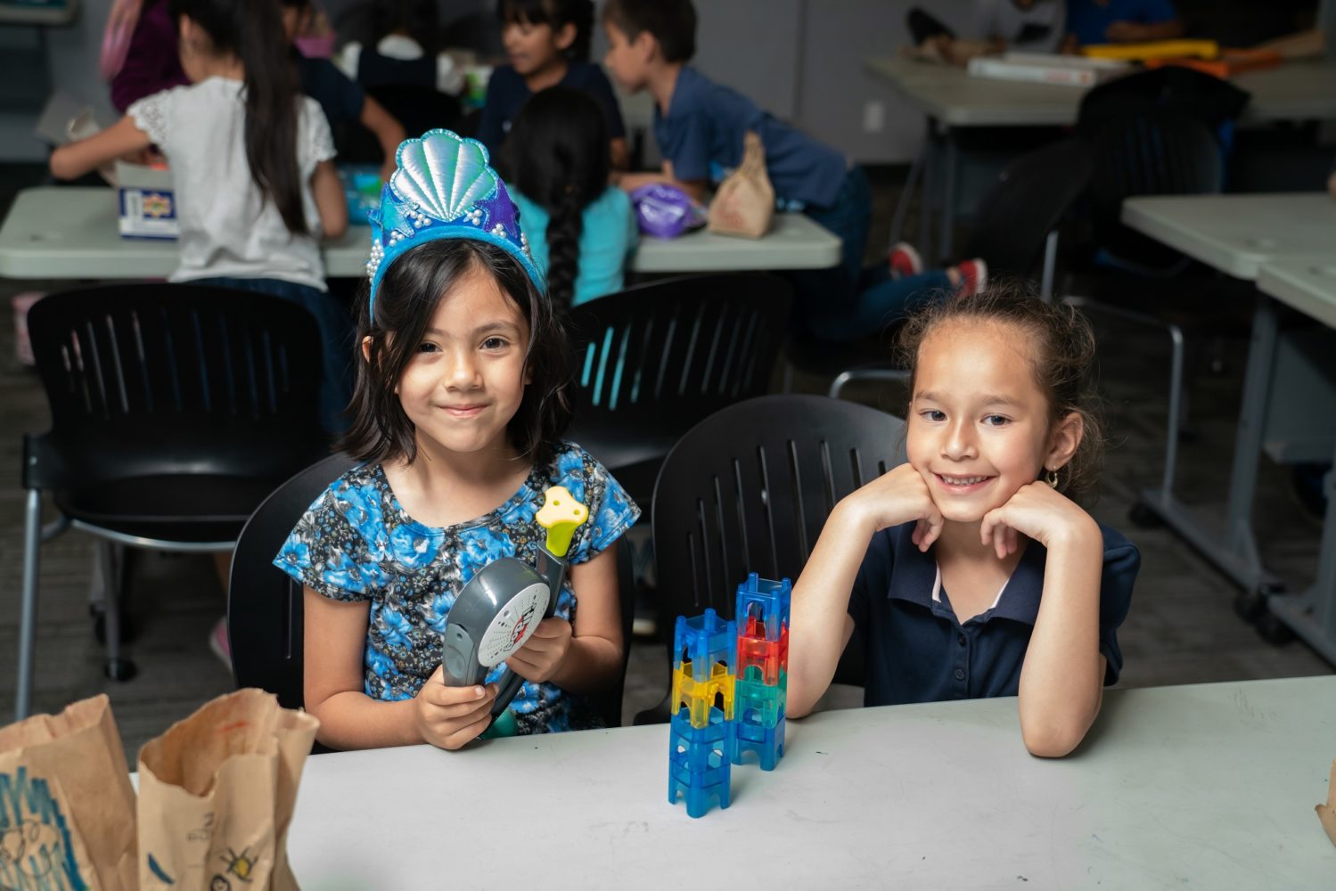 Two girls doing an activity and smiling at the camera